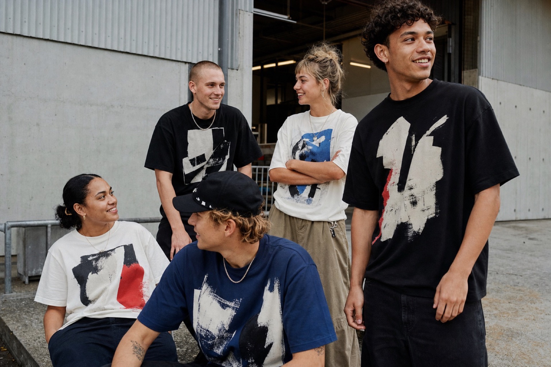 A group of young people wearing graphic T-shirts outside a creative studio