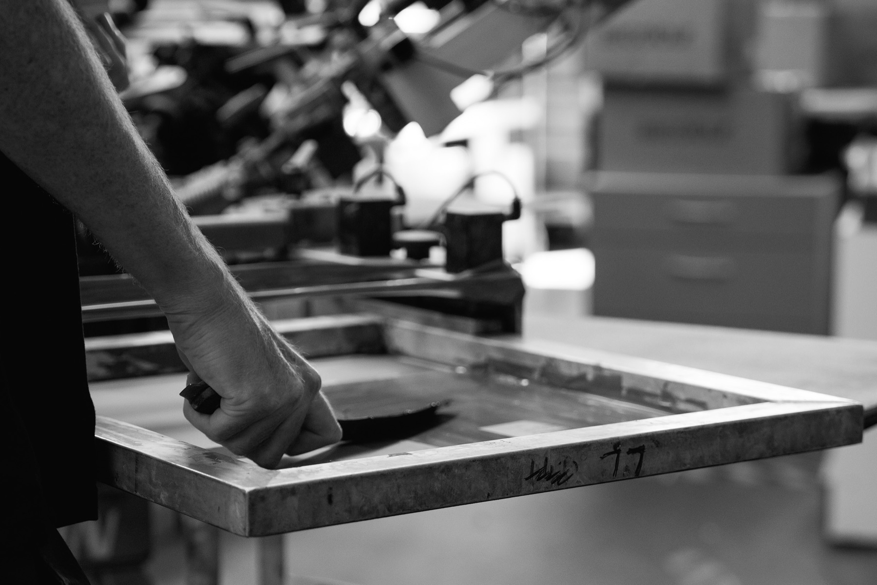 A printmaker working by hand at a screen printing station